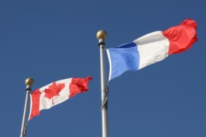 The flags of Canada and France against a blue sky
