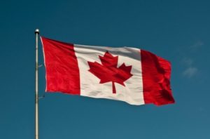 A Canadian flag waving against a bright blue sky