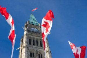 Three Canadian flags blowing in the wind in front of Parliament Hill, Ottawa, Ontario, Canada