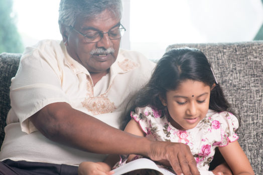 Grandparent and grandchild reading a story book together.