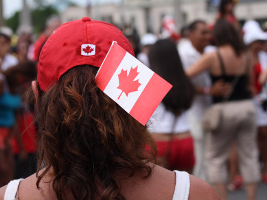 A woman watching others dance in the street on Canada Day in Ottawa, Ontario.