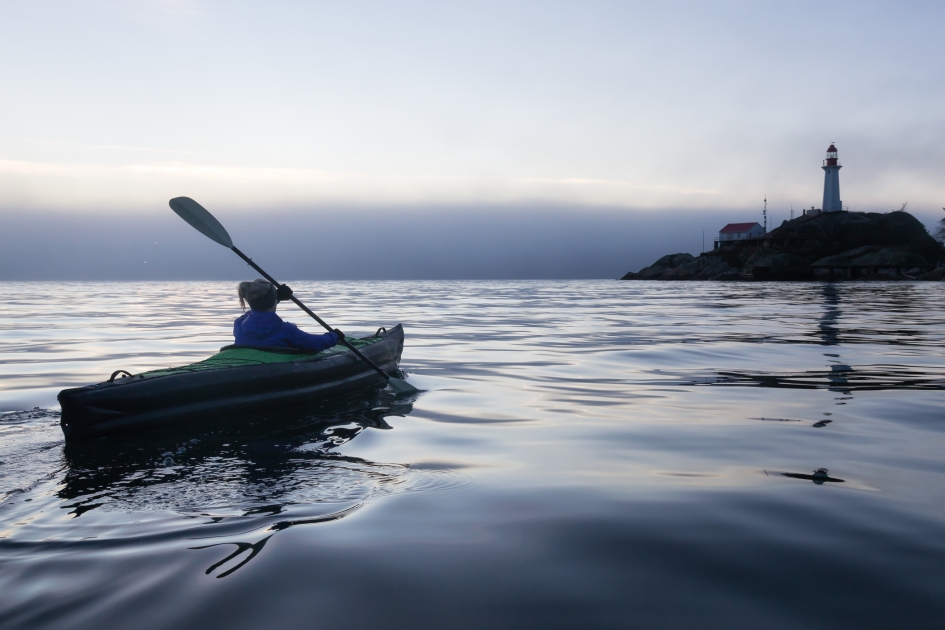 A kayaker paddles at sunset in British Columbia