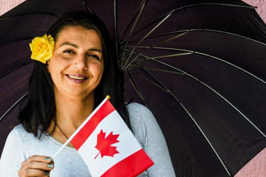 Woman holding small Canadian flag, smiling