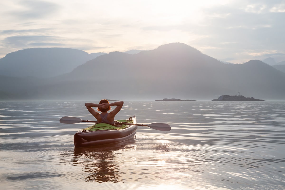 Woman relaxing on Kayak, enjoying Canadian mountain landscape