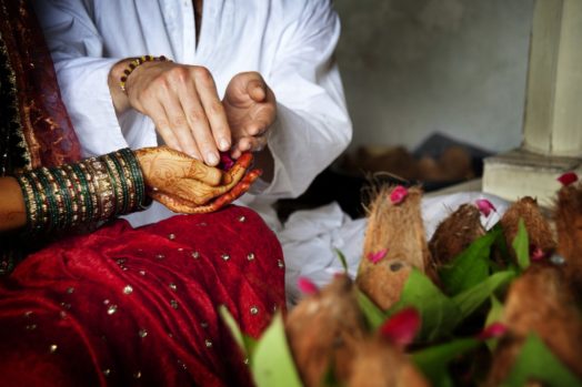 Close-up of groom putting rose petals in brides hands
