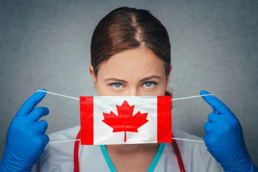 Woman putting on COVID safety mask decorated with a Canadian flag