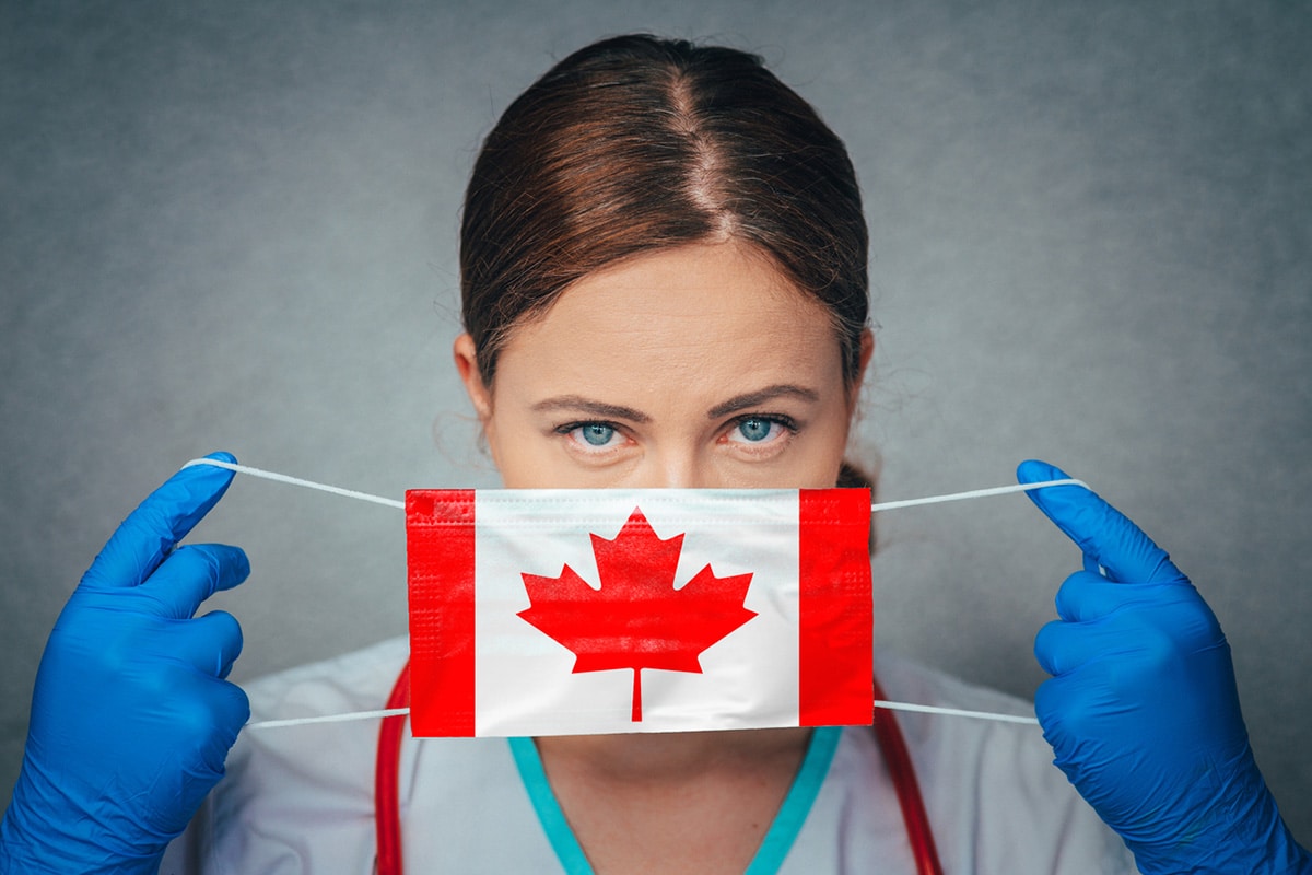 Woman putting on COVID safety mask decorated with a Canadian flag