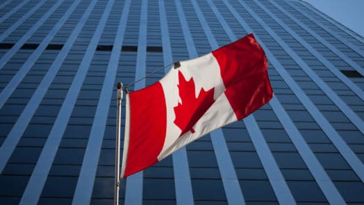 Canadian flag flapping in the wind in front of a building