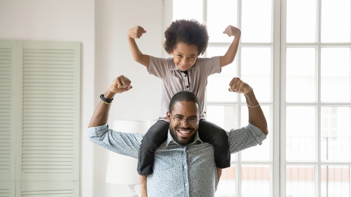 Boy on his dad's shoulders, flexing his muscles.