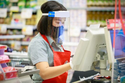 Woman working grocery store wearing covid protective gear