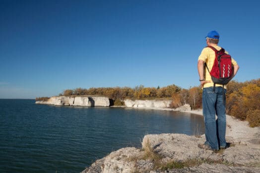 Man overlooking Manitoba lake on limestone beach.