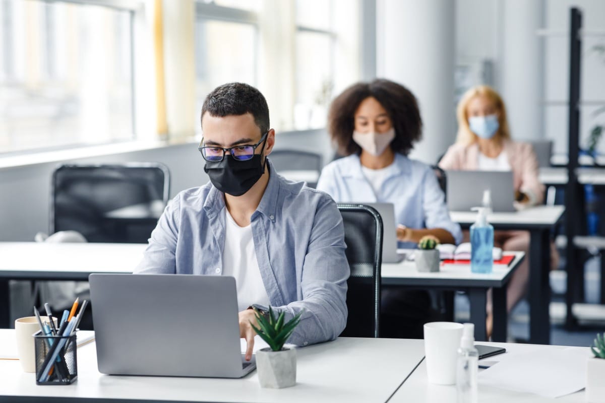 Employees working on computers wearing surgical masks.
