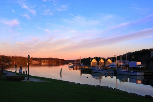 Landscape of Prince Edward Island showing boats in water under the sunset.