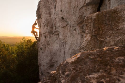 A Silhouette of a Woman rock climbing on Ontario's Niagara Escarpment in Canada