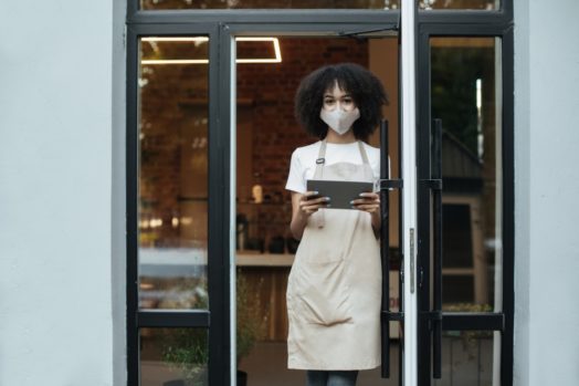 Black female business owner, holding tablet, wearing surgical mask