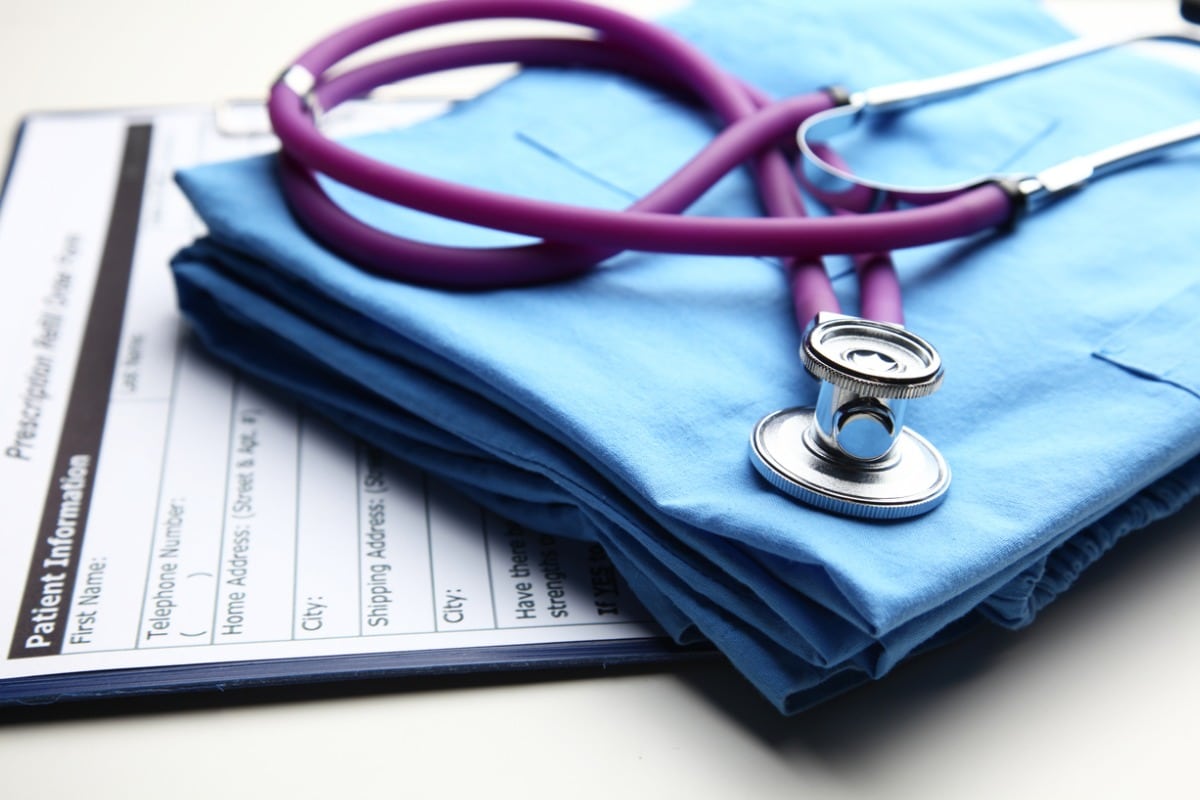 Medical gown and stethoscope on top of patient information papers.