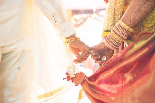 The hands of two newly-weds latched to each other's pinky fingers.