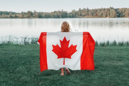 Girl holding Canadian flag near a lake.