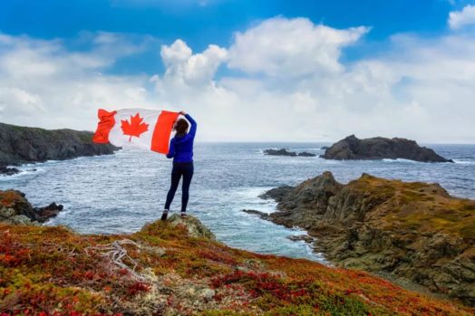 Person holding Canada flag on coast.