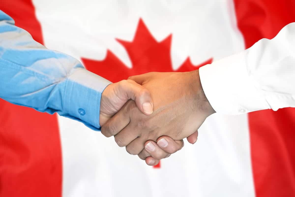 Shaking hands in front of a Canadian flag
