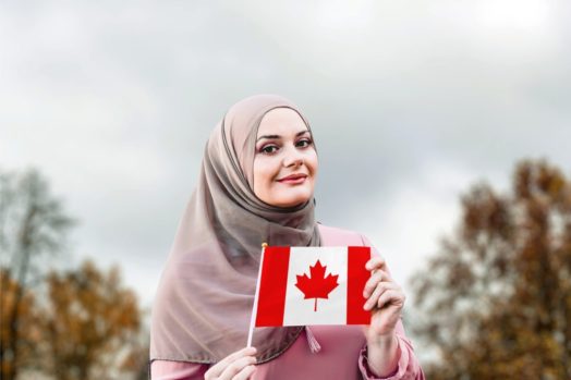 woman in hijab holding a small Canadian flag