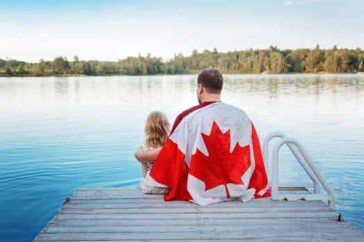 Father and daughter wrapped in large Canadian flag