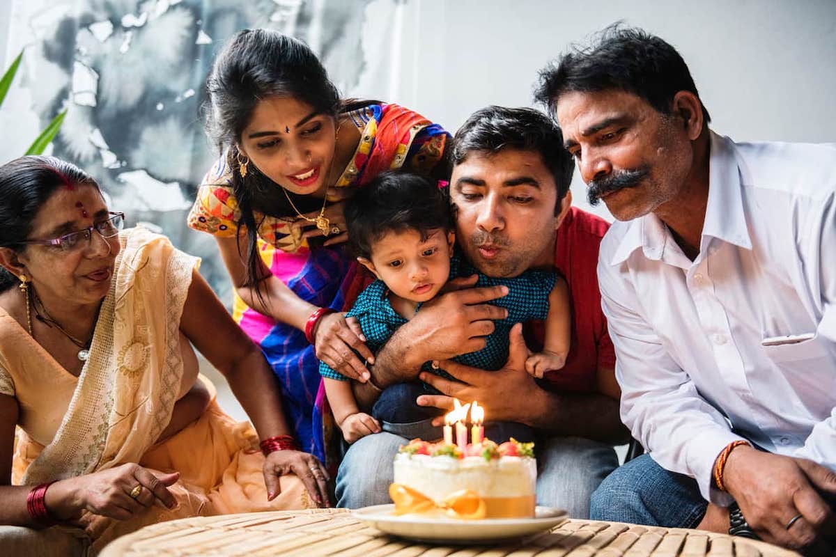 Indian parents, grandparents, and child in front of birthday cake