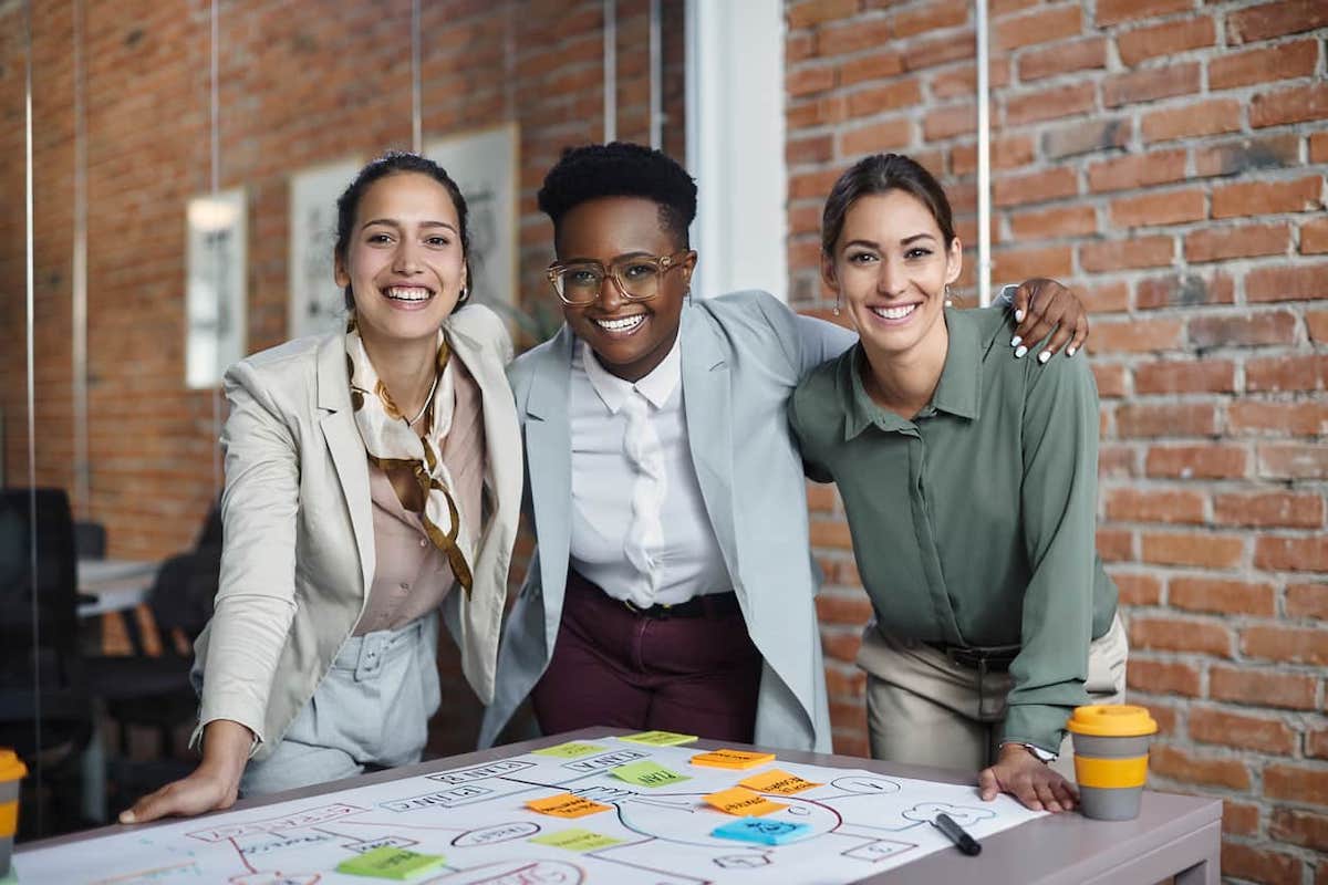 Three women in business attire looking at the Camera. The significant work permit is available for those whose work would provide significant benefit to Canada.