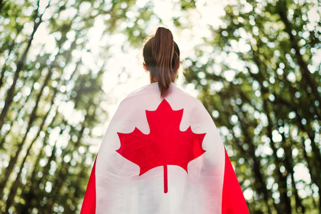 A woman in the woods with a Canadian flag on her back. Over 90% of the Canadian population are naturally born citizens.