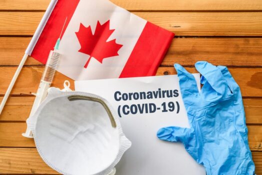 Canadian flag, medical glove, paper with coronavirus written on it and an N95 mask