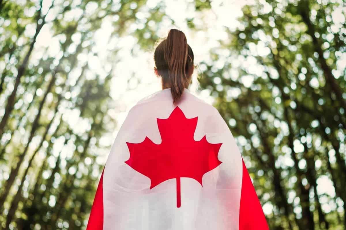 person standing facing away from the camera with Canadian flag draped over their back