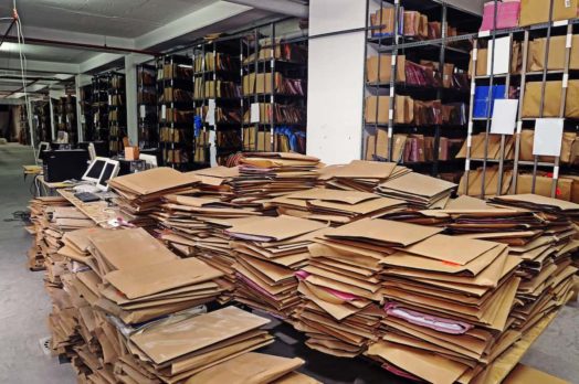 Un montón de archivos antiguos en medio de una sala de archivos.  IRCC ha asignado casi 60,000 solicitudes a oficiales inactivos.