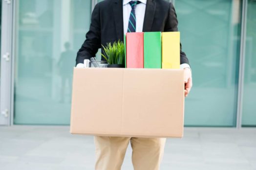Un hombre que sostiene una caja llena de material de oficina al salir de su trabajo.  La mayoría de las personas en Canadá no dejan su trabajo debido a los despidos.