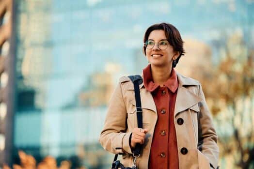 Una mujer parada afuera de un edificio comercial con una bolsa en la mano.  El empleo de nómina continúa aumentando en Canadá, una buena señal de una mayor contratación en el país.