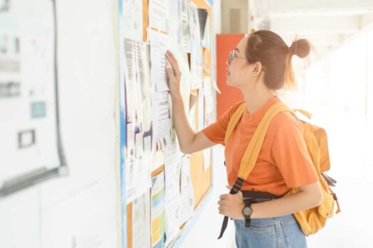 A student looking at a posting board at their university. International students can now work an unlimited number of hours in Canada, until the end of 2023.