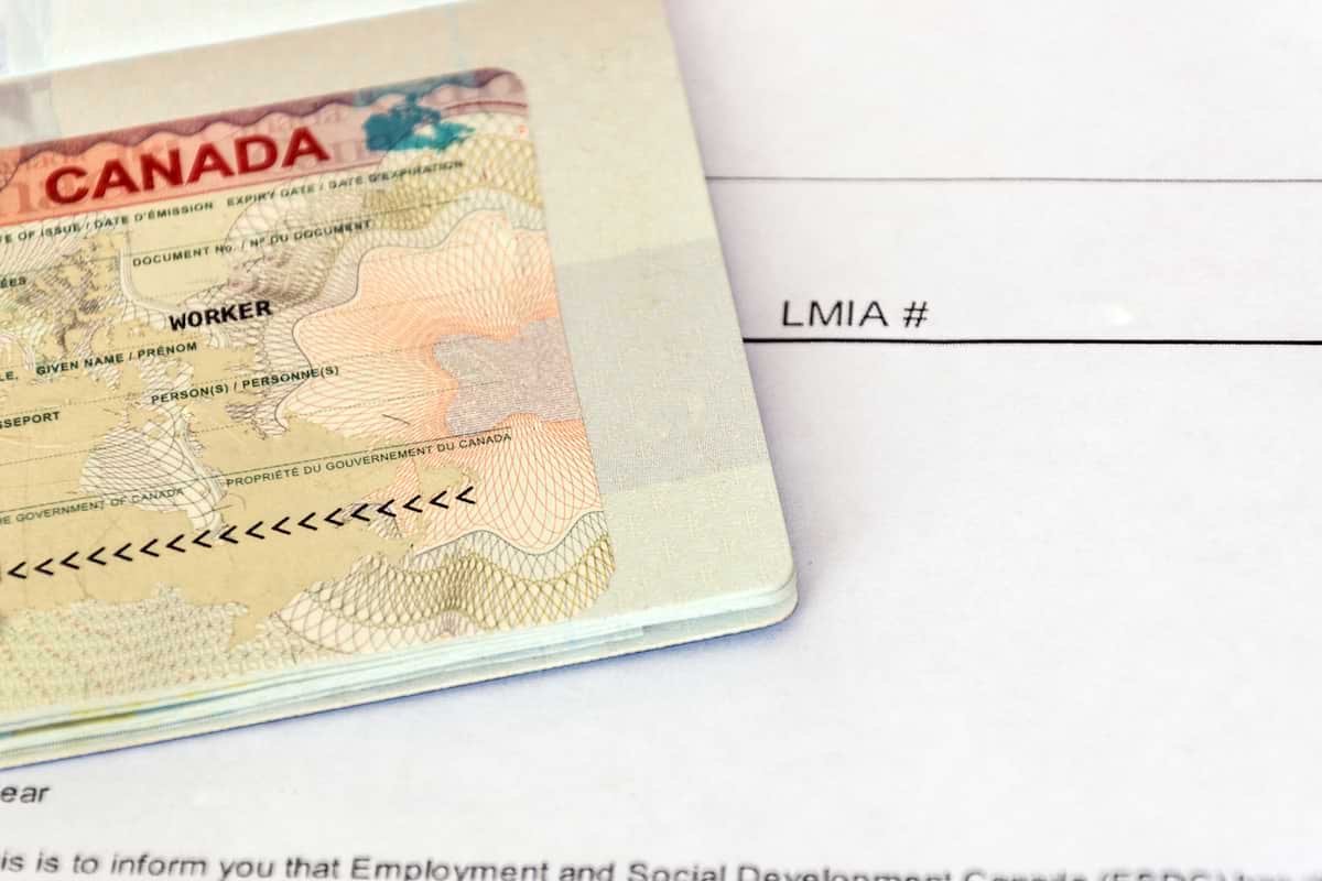 A Canadian Visa in passport, with LMIA documentation in the background. In 2022, Canada issued over 600,000 work permits.