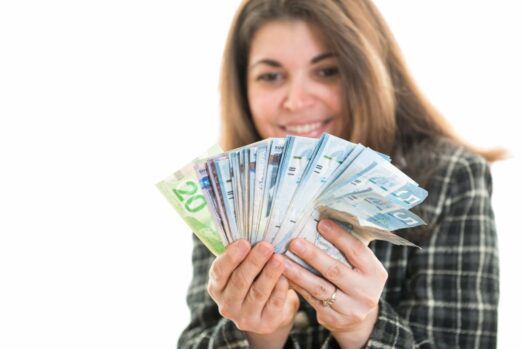Mujer sosteniendo billetes de dólares canadienses en abanico en ambas manos