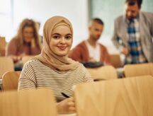 Smiling female student in hijab attending a lecture at the university and looking at camera
