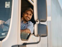 Happy truck driver looking through side window while driving his truck
