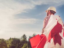 An engineer holding a Canadian flag as he looks forward into the sky.