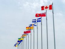 A row of provincial flags blowing majestically in the wind, with the national flag at the forefront