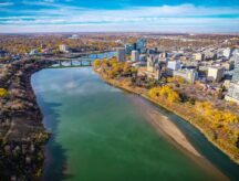 An aerial view of Saskatoon, featuring the river and bridge overpass.