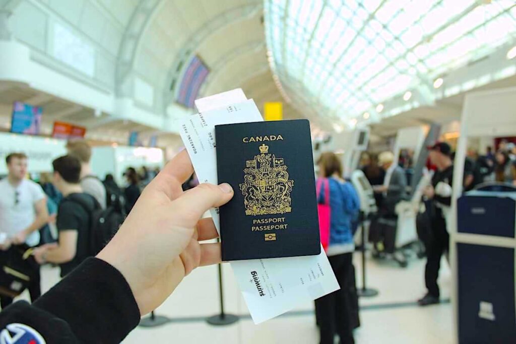 A man holds his passport up at the airport as he travels through customs. Canada has one of the most recognised passports from any country around the world.