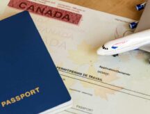 A blank passport and model airplane placed on top of a permit. Read on your guide to returning to Canada after the holidays.