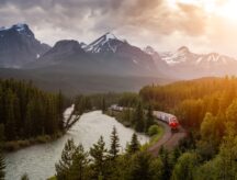 Iconic View of Morant's Curve with Train Passing and Canadian Rocky Mountain Landscape in the background during colorful sunset