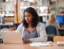 A female student working at a laptop in a school library. We answer some top questions around IRCC's new announcement.