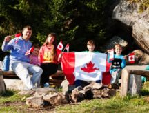 Family with large Canadian flag celebration in mountains