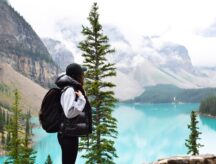 girl with backpack admiring the beauty of turquoise blue Moraine lake and mountains in Banff