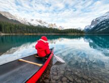 Rear view of male tourist in red winter coat canoeing with paddle in Spirit Island on Maligne Lake at Jasper national park, Alberta, Canada