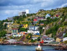 A coast in Newfoundland interspersed with homes. Canada has extended the ban on foreign buyers of residential property.